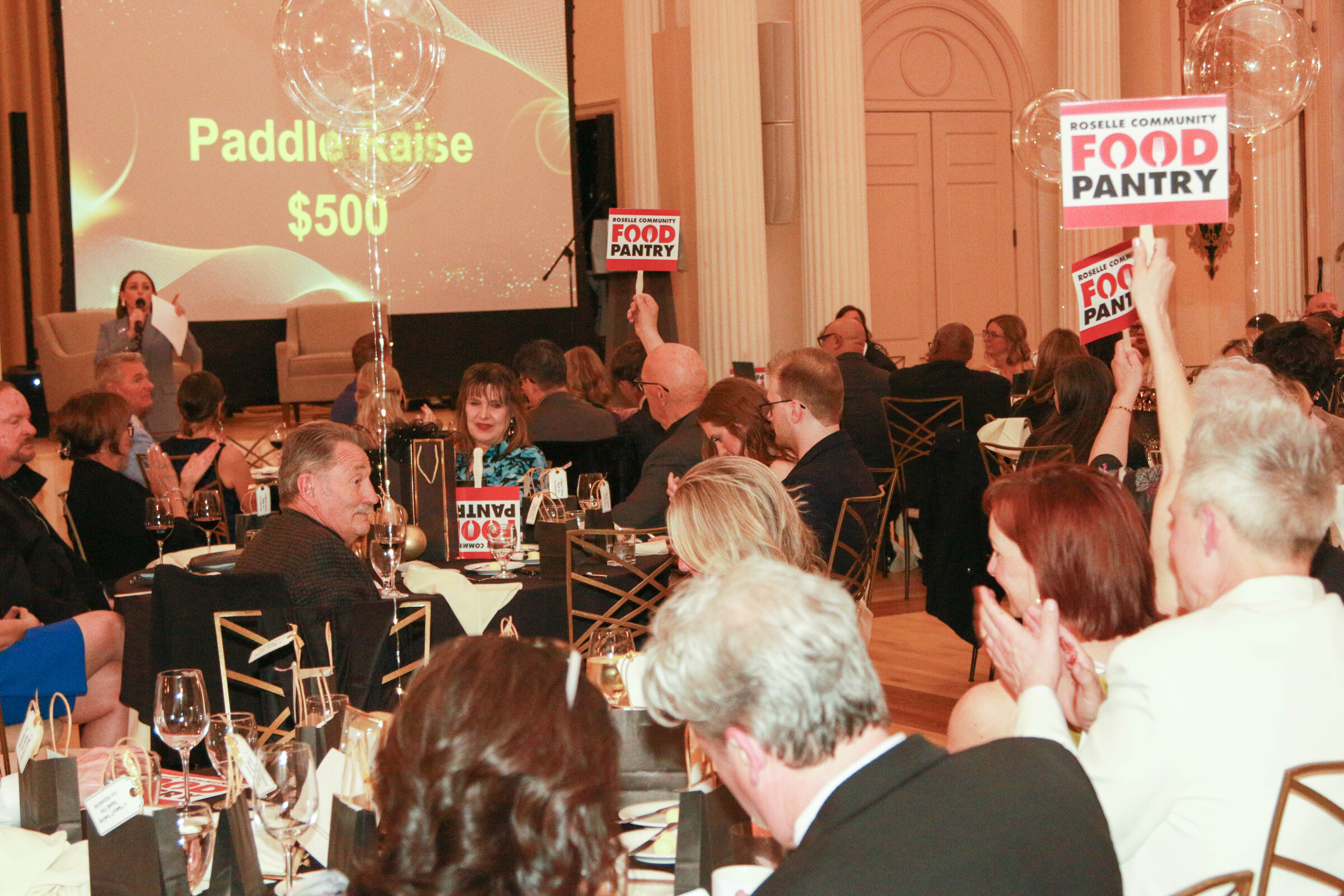 Guests raising their paddles during a fundraising appeal